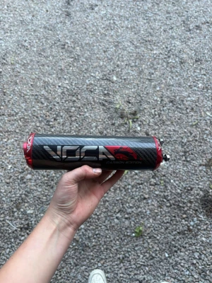 Voca Carbon Edition ljuddämpare - Säljer en Voca Carbon Edition ljuddämpare med kolfiberhölje och röda aluminiumändar. Cylindrisk form och tydlig Voca-logga på sidan. Passar till moped eller scooter och ger ett sportigt utseende.