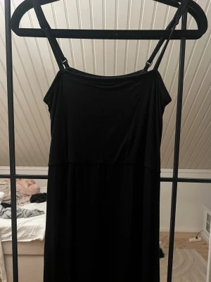 Svart klänning från Gina Tricot - Svart klänning från Gina Tricot med smala axelband och enkel, stilren design. Klänningen har en rak passform och är tillverkad i mjukt tyg som faller snyggt. Perfekt för dig som gillar minimalistisk stil.