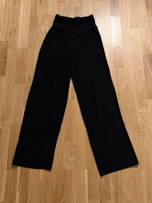 Svarta vida byxor från SOC - Säljer ett par svarta byxor från SOC med hög midja och vida ben. Byxorna är mjuka och stretchiga, perfekta för en avslappnad stil. Passar dig som gillar bekväma och stilrena plagg. Materialet känns lent och följsamt. Köpta på stadium för många år sedan. Det är typ träningsbyxor men går även använda som vanliga byxor. Dom har inga fickor.          Katt finns i hemmet!!
