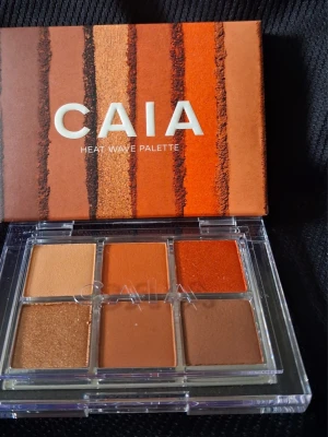 CAIA Heat Wave ögonskuggspalett - Snygg ögonskuggspalett från CAIA med sex nyanser i varma toner som beige, koppar, orange, brons och brunt. Paletten har både matta och skimrande skuggor i fyrkantiga pans, perfekt för kreativa ögonlooks. Kommer i en stilren förpackning med transparent lock.