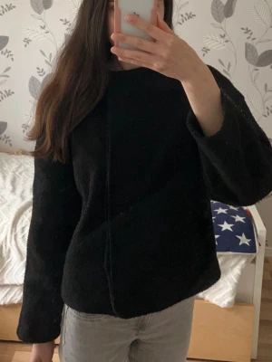 Svart höstjacka Nelly - Säljer en svart höstjacka med rund halsringning och stora knappar framtill. Jackan har en rak, boxig passform och är tillverkad i ett mjukt, lite fluffigt material 😊
