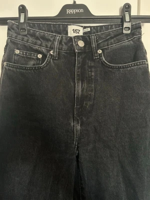 Svarta raka jeans med hög midja - Säljer ett par svarta jeans med raka ben och hög midja. Jeansen har klassisk femficksmodell, silverfärgade nitar och tydliga sömmar. Materialet är kraftig denim i bomull. Perfekta för en avslappnad och trendig look.