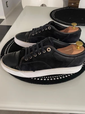 Lanvin skor  - Jag säljer ett par riktigt snygga svarta/ mörkblåa lanvins som passar till typ allt. Perfekta om du gillar clean outfits. Dem är använda men fortfarande riktigt fräscha och har mycket kvar att ge. Skornas små skavanker sitter inuti skon på, där man ser att sulan inuti blivit skadad, annars är skorna i fint skick. Nypriset är betydligt högre, ett bra tillfälle och vara snabb och plocka hem ett par fräscha lanvins, vid frågor och funderingar är det bara att kontakta mig.