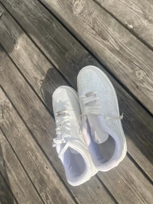 Vita klassiska sneakers i läder - Snygga helvita sneakers i läder med lågt skaft och perforerade detaljer på tån. Skorna har vita snören och en stilren design som passar till det mesta. Yttersulan är vit och insidan är fodrad i vitt tyg. Perfekta för en clean och fräsch look.