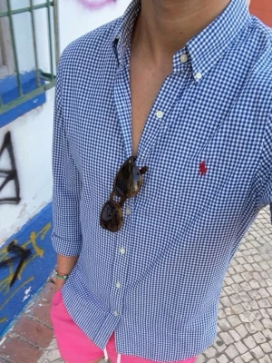 Blårutig skjorta från Polo Ralph Lauren - Säljer en blårutig skjorta från Polo Ralph Lauren i slim fit. Skjortan har klassisk krage, knappar framtill och den ikoniska röda loggan broderad på bröstet. Tillverkad i bomull och perfekt för en clean och stilren look.