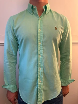 Ljusgrön skjorta från Ralph Lauren - Snygg ljusgrön skjorta från Ralph Lauren. Skjortan är tillverkad i mjuk bomull. Perfekt för en clean och fräsch look. Skjortan är i mycket bra skick och passar perfekt nu under sommaren