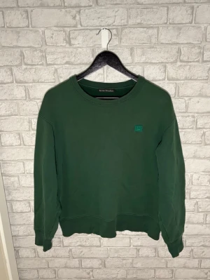 Acne Studios tröja - Acne Studios sweatshirt i en snygg mörkgrön färg med klassiska Face-loggan på bröstet. Skön passform och fint skick. Hör av dig vid intresse!🙌