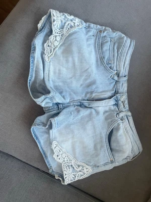 Ljusblå jeansshorts med spetsdetaljer - Snygga ljusblå jeansshorts med unika virkade spetsdetaljer på sidorna. Klassisk femficksmodell med dragkedja och knapp. Perfekta för sommaren🌸💕