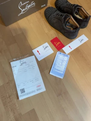 Christian Louboutin svarta sneakers - Säljer ett par svarta sneakers från Christian Louboutin i mocka med ikoniska röda sulor och nitar framtill. Skorna har snörning och en clean, lyxig look som sticker ut. Perfekta för dig som vill ha något unikt och trendigt, är öppen för frågor och om du vill diskutera priset🙂