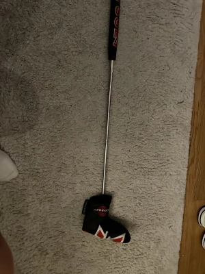 Odyssey golfputter svart/röd - Säljer en Odyssey golfputter med svart och rött grepp och matchande headcover. Skaftet är i metall och puttern har en modern design med tydliga vita och röda detaljer. Perfekt för dig som vill förbättra ditt spel på greenen.