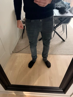 Nudie jeans Mörkgråa - Säljer ett par mörkgrå  nudie jeans med klassisk femficksmodell och dragkedjegylf. Jeansen har en smal passform som sitter snyggt längs benen och är perfekta för en modern look. Materialet är mjukt denim som ger bra komfort hela dagen.