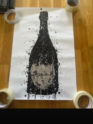 Poster med svart flaskmotiv - Säljer en poster med ett konstnärligt svart motiv av en flaska på vitt papper. Trycket har stänkeffekter och en detaljrik etikett i mitten. Perfekt som cool väggdekoration för dig som gillar modern konst och grafiska tryck.