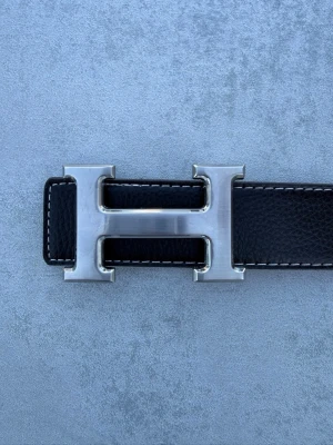Herme’s bälte - Ett svart herme’s bälte med silverfärgat spänne, ett sjukt snyggt bälte som passar till både vardags och finare outfits.