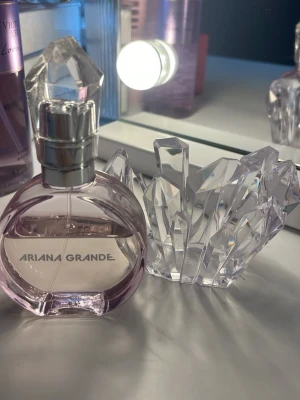 Ariana Grande parfym kristallflaska - Säljer en Ariana Grande parfym i en rund, ljuslila kristallformad flaska med silverfärgat lock. Flaskan har en unik design som påminner om slipade kristaller och ger ett lyxigt intryck. Perfekt för dig som gillar snygga detaljer på sminkbordet.använt några få gånger säljer för den används längre pris går att diskuteras,💕