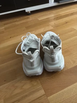 Vita Nike reacts - Säljer ett par helvita sneakers med ventilerande mesh-ovandel och klassisk snörning. Skorna har dragflikar både fram och bak för enkel påtagning samt en chunky sula som ger en modern look. Perfekta för dig som gillar stilrena och sportiga skor.