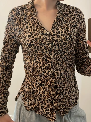 Leopardmönstrad långärmad blus - Snygg leopardmönstrad blus med krage och knappar framtill. Blusen har långa ärmar och är tillverkad i ett lätt, stretchigt tyg som sitter figurnära. Perfekt för dig som vill sticka ut med ett djurmönster.