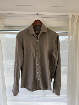 Sonrisa - Stilren beige skjorta från Sonrisa med klassisk krage och vita knappar. Skjortan är långärmad och har en enkel, tidlös design som passar till många olika looks. Tillverkad i mjuk bomull för en bekväm känsla.