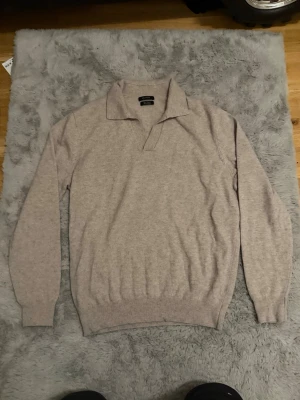 Beige stickad tröja från Massimo Dutti - Säljer en stilren beige stickad tröja från Massimo Dutti i mjuk kashmir. Tröjan har lång ärm, klassisk krage och ribbade muddar vid ärmslut och nederkant. Perfekt för dig som gillar en clean och tidlös look.