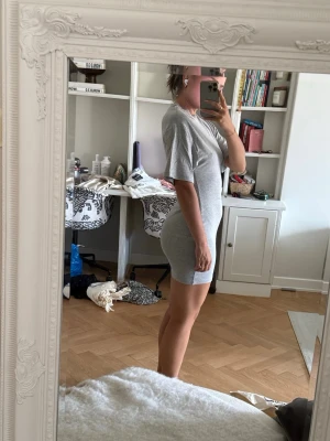Grå tight kortklänning - Säljer en enkel och stilren grå kortklänning med rund hals och korta ärmar. Klänningen har en tight passform och är gjord i ett mjukt bomullsliknande material. Perfekt för en avslappnad och trendig look. Aldrig använd!