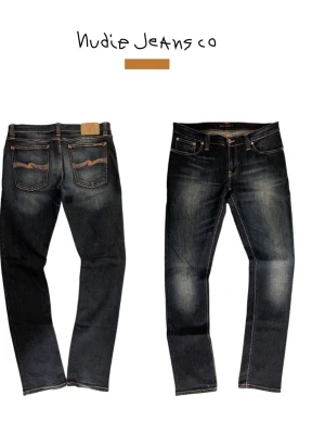 Mörkblå jeans från Nudie Jeans - Snygga mörkblå jeans från Nudie Jeans med klassisk femficksmodell och kontrastsömmar. Jeansen har raka ben och coola slitningar framtill samt Nudie-logga broderad på bakfickorna. Tillverkade i slitstark denim, perfekta för en avslappnad stil.