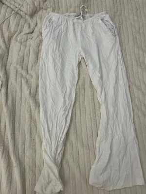 Vita linnebyxor från 157, XS - Säljer ett par vita linnebyxor från 157 i storlek XS. Byxorna har resår i midjan med dragsko och två sidofickor. De är raka i modellen och har en avslappnad passform. Perfekta för en chill och bekväm stil.