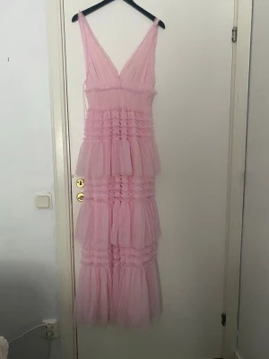 Lång rosa volangklänning - Säljer en lång rosa klänning med flera lager av volanger och v-ringad urringning. Klänningen är använd en gång och är som ny🥰💕ordinarie pris 1800 kr