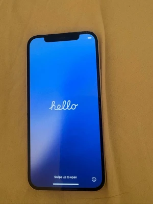IPhone 12 vit - Säljer en vit iPhone med stilren design och två kameror på baksidan. Telefonen har en stor skärm med tunna kanter och Apple-loggan på baksidan. Perfekt för dig som gillar snygg och modern teknik.