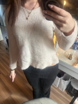 Ljusbeige fluffig stickad tröja - Mysig ljusbeige stickad tröja med fluffig yta och rund hals. Tröjan har långa ärmar och en avslappnad passform, perfekt för att hålla värmen under kyliga dagar. Passar till både jeans och kjol. Säljer den då den är för liten för mig och kommer då inte till användning