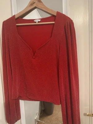 Röd glittrig topp från Bubbleroom - Snygg röd topp från Bubbleroom med glittrigt tyg och lång ärm.
