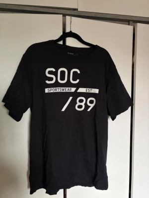 Svart t-shirt från SOC med tryck - Säljer en svart t-shirt från SOC i storlek L med vitt tryck framtill där det står 'SOC SPORTSWEAR EST /89'. 
