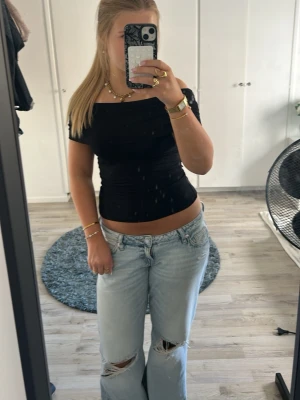 Svart offshoulder topp - Snygg svart offshoulder topp med tight passform och korta ärmar. Toppen är croppad och har en bred kant över axlarna som ger en trendig look. Perfekt att matcha med jeans eller kjol för en cool stil.💕