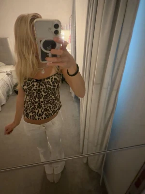 Leopardmönstrat linne med svarta band - Säljer ett leopardmönstrat linne med tunna svarta axelband och svart kant upptill. Linnet har en figurnära passform som sitter snyggt på kroppen. 