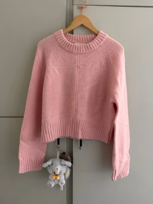 Ljusrosa stickad tröja SEZANE  - Mysig ljusrosa stickad tröja. Tröjan har en rak och boxig passform och långa ärmar. Storlek XL men ganska liten i storleken. Använd 1 gång så nyskick. 