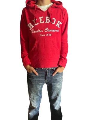Röd Reebok hoodie med tryck - Röd hoodie från Reebok med vit text 'Canton Campus Since 1895' på bröstet. Klassisk känguruficka framtill, huva med dragsko och ribbade muddar. Perfekt för en sportig och avslappnad stil.