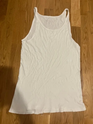 Vit ärmlös linnetopp - En basic vit linnetopp i mjuk bomull med klassisk rund halsringning och ärmlös design. Perfekt att styla lager på lager eller bära som den är under varma dagar.🤍