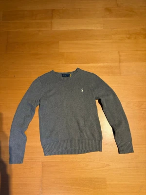 Grå stickad tröja Polo Ralph Lauren - Klassisk grå stickad tröja från Polo Ralph Lauren med rund halsringning och diskret broderad logga på bröstet. Priset är inte hugget i sten🙌