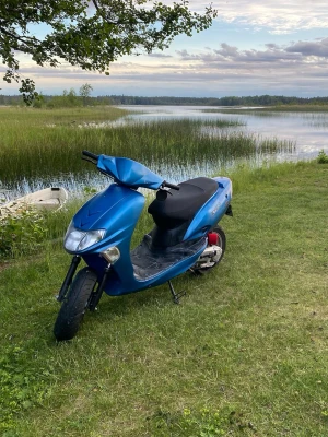 Vitality kymco moped - En blå scooter med svart sits och sportig design.  framlykta och röda detaljer vid bakhjulet. Perfekt för dig som vill ta dig fram snabbt och smidigt. Passar bra för både stad och landsbygd. Funkar ej men lätt projekt. Vitality kymco 50 2 T. skriv för mer info!