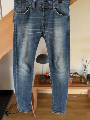 Dondup  jeans med slitningar  - Snygga blå jeans med slitningar på låret och även på backfickan. Det är fina faders som sticker ut i mängden  jeansen kommer som ni kan se på bilderna.