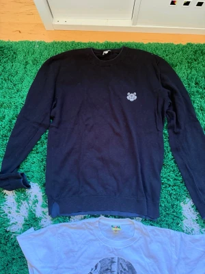 Svart kenzo tröja. Skriv för mer info eller bilder  - En svart sweatshirt med rund hals och ett litet broderat kenzo märke på bröstet. Tröjan har långa ärmar och ribbade muddar vid ärmslut och nederkant. Perfekt för en avslappnad stil och enkel att matcha med jeans eller byxor.