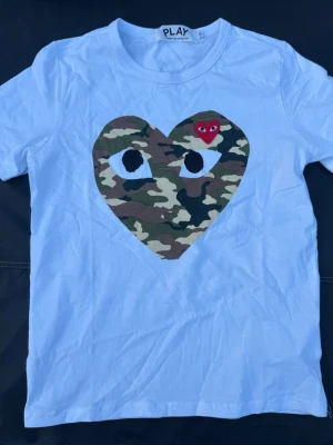 Comme des gracons t shirt  - Comme des gracons t shirt i vit färg med cammo hjärta is storlek S 