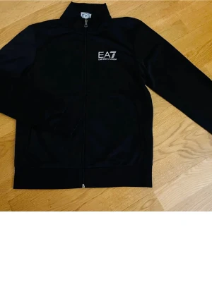Svart  EA7 Emporio Armani - Svart kedjetröja från Emporio Armani EA7. Perfekt för höst och vinter. Köpt i butik i Sverige. Inga fel eller skador på tröjan. Använd sparsamt och är i nyskick