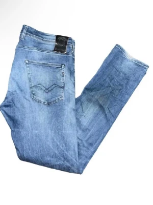 Replay jeans  - Säljer ett par Replay Grover jeans i ljusblå tvätt med klassisk femficksdesign och snygga slitningar. Jeansen har raka ben och normal passform, med Replay-logga på bakfickan och läderpatch i midjan. Perfekta för dig som gillar en avslappnad stil. Midja 45cm, längd 107cm OBS, jeansen har fläckar som syns på en utav bilderna och även har lite fåll alltså slitningar längst ned på benen på baksifan :)