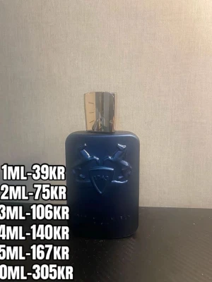 Mörkblå parfymflaska med silverlock - Snygg parfymflaska i mörkblått med ett elegant silverfärgat lock. Flaskan har en upphöjd logga med två hästar och svärd på framsidan, vilket ger en exklusiv känsla. Perfekt för dig som gillar stilrena och lyxiga dofter.