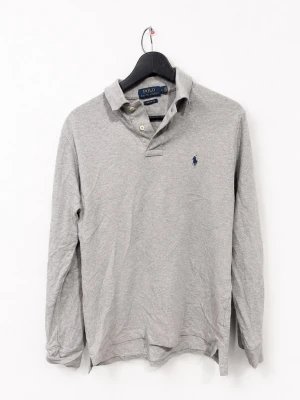 Polo Ralph Lauren Custom Slim Fit Långärmad Piké Grå – S - Grå långärmad pikétröja från Polo Ralph Lauren i Custom Slim Fit, storlek S. Klassisk modell med krage, knappslå och broderad Polo-logga på bröstet. Stilren grå färg och en lättmatchad modell som fungerar både till vardags och mer uppklätt.  Fint begagnat skick enligt bilderna.  📦 Snabb frakt 💬 Bud välkomnas ♻️ Fler utvalda märkesplagg finns på profilen