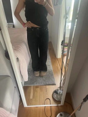 Svarta raka jeans med kontrastsömmar - Säljer ett par svarta jeans med raka ben och vita kontrastsömmar. Jeansen har klassisk femficksdesign och normal midja. Perfekta för dig som gillar en avslappnad och stilren look.