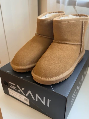 Helt nya ALLY W - platta ankelboots - Exani Ally W - Storlek 38 Helt nya och oanvända vinterboots från Exani, med originalkartong och prislappar kvar. * Storlek: 38 * Färg: Yellow/Camel * Äkta läder/mocka, vattenavvisande * Varmt ullblandat foder * Rejäl gummisula med bra grepp * Klassisk design, liknande UGGS Ordinarie pris: 1299 kr. Perfekta för höst och vinter! Skickas snabbt Vill du se fler bilder är det bara att höra av dig!