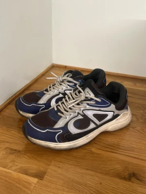 B30 - Navyblå sneakers i B30-modell med vita och svarta detaljer. Storlek 42. Skorna är lite smutsiga och är slitna på insidan vid hälen, se bilderna för skick. Säljs utan originalkartong.