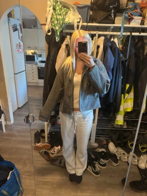 Grå croppad ulljacka med knappar - Säljer en grå croppad jacka i ull med stora fickor framtill och knäppning med knappar. Jackan har klassisk krage och lång ärm, perfekt för dig som gillar en stilren och enkel look.