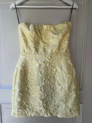 Strappless klänning  - Jättesöt gul strappless klänning med broderade blommor och figursydd passform. Aldrig använd! 💛🤍