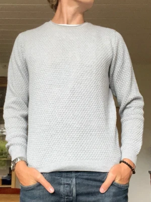 Stenströms stickad tröja i ljusgrå - stl M - Stenströms stickad tröja i ljusgrå, storlek M. 100% Bomull. Prickig struktur över hela plagget, ribbad hals, muddar och nederkant.  Använd men i mycket fint skick, inga hål eller fläckar. Personen på bilden är 189cm, väger 78kg.  Rök- och djurfritt hem. Skriv gärna om du vill ha fler bilder eller undrar något!